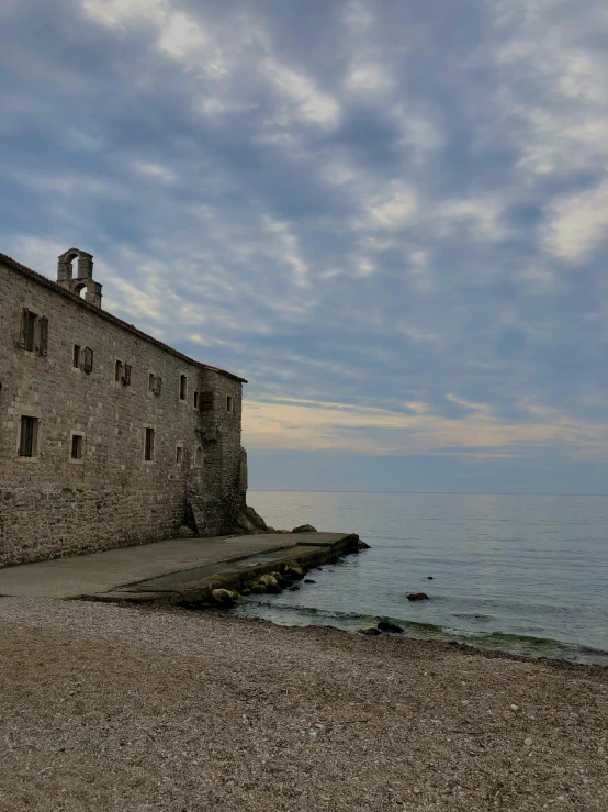 an old building sits in front of the ocean