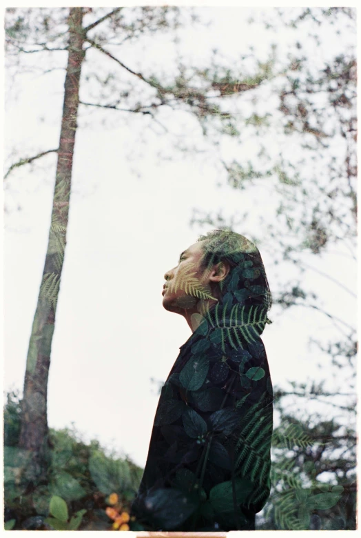 a woman looking up into the sky next to trees