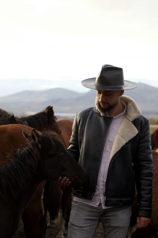 a man standing next to a horse wearing a leather jacket