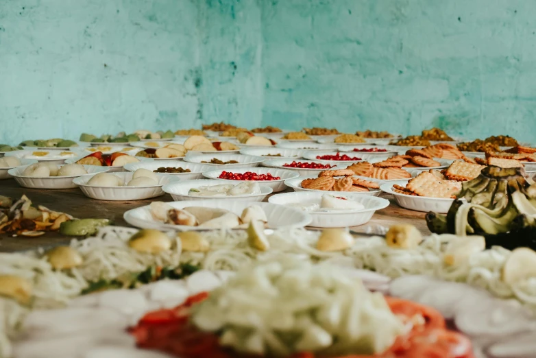 lots of plates and bowls on the floor full of food