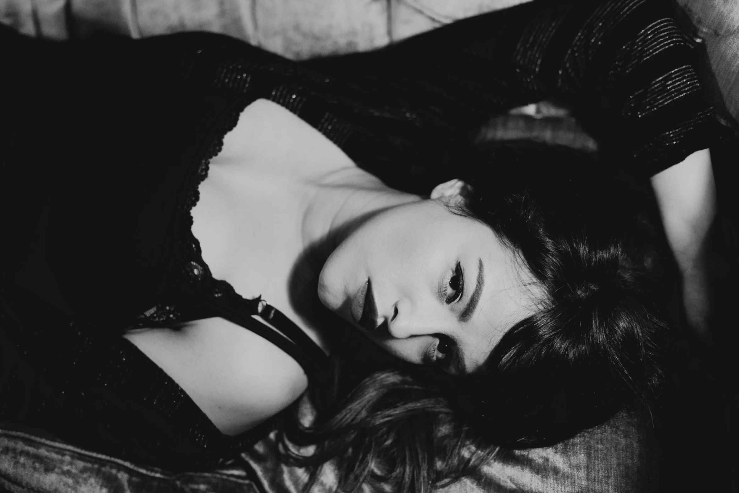 a woman is posing on a couch in black and white