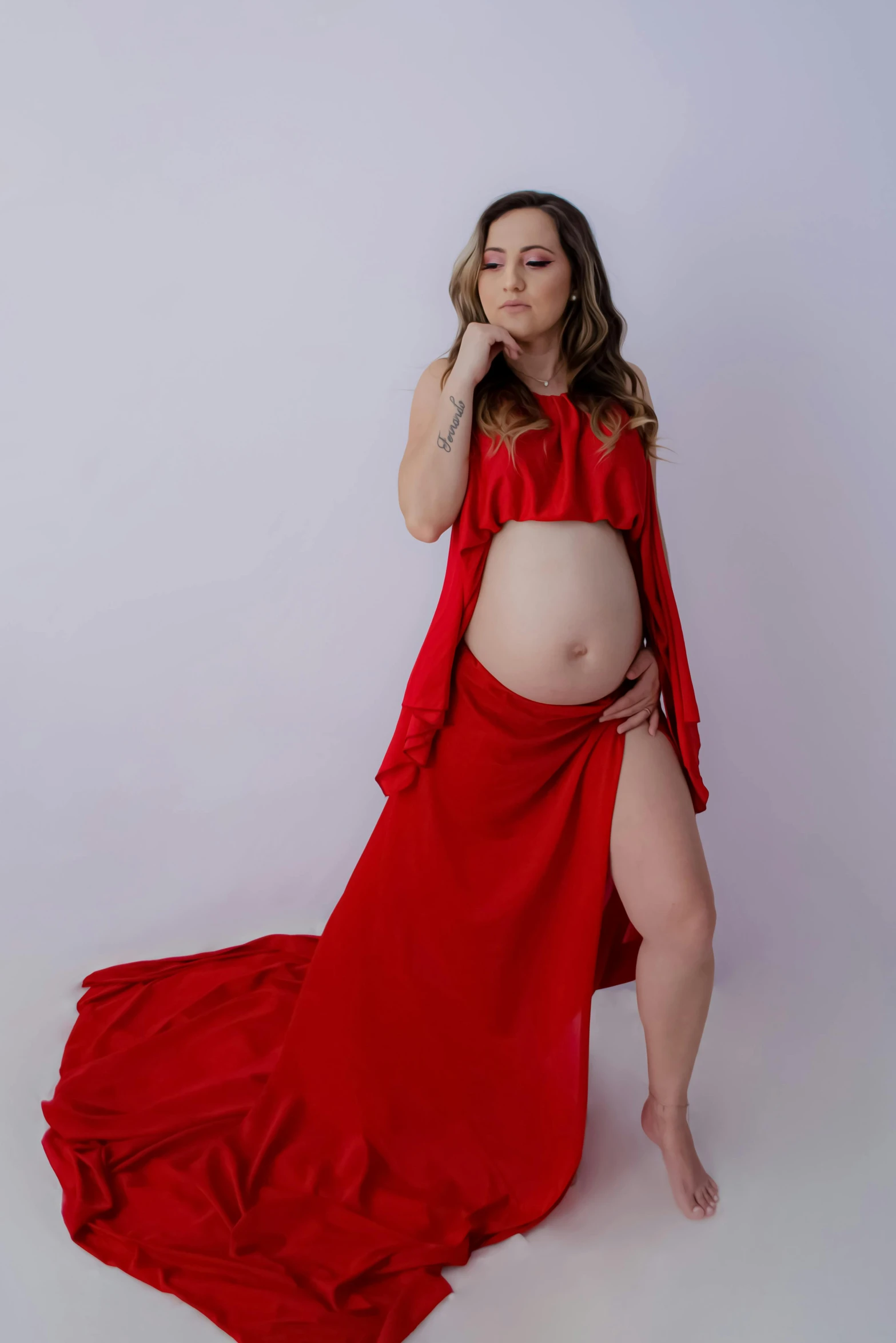 a pregnant woman in a red gown poses for a po