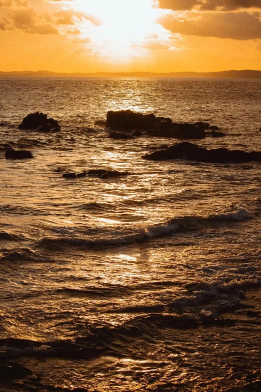 a sun sets over a body of water with the ocean in the foreground