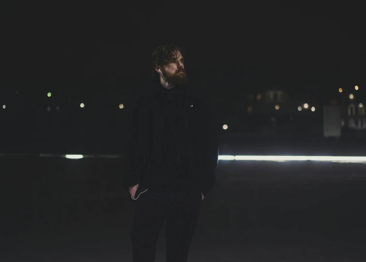 man in black coat and pants standing by the water