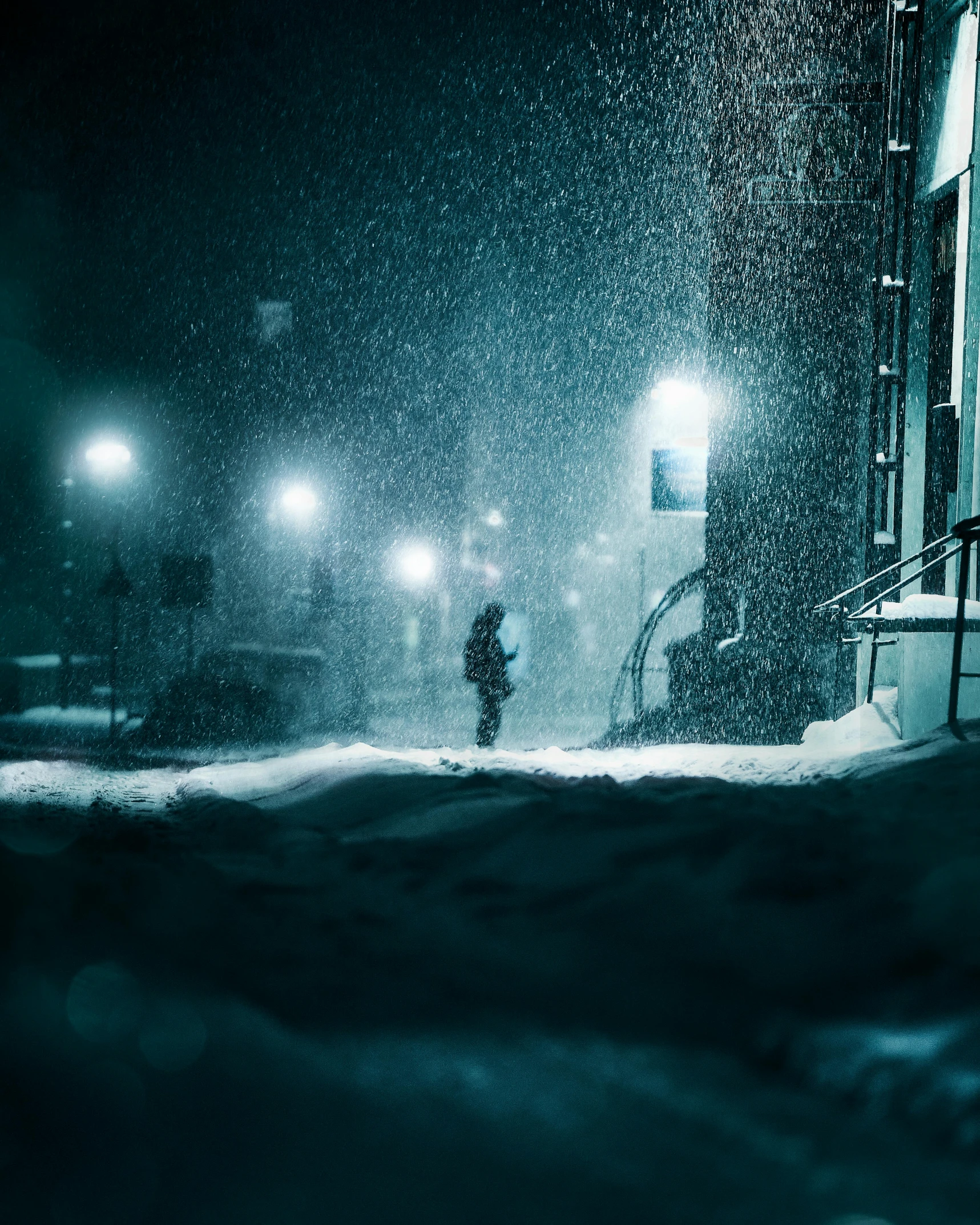 man walking through snow at night on city street