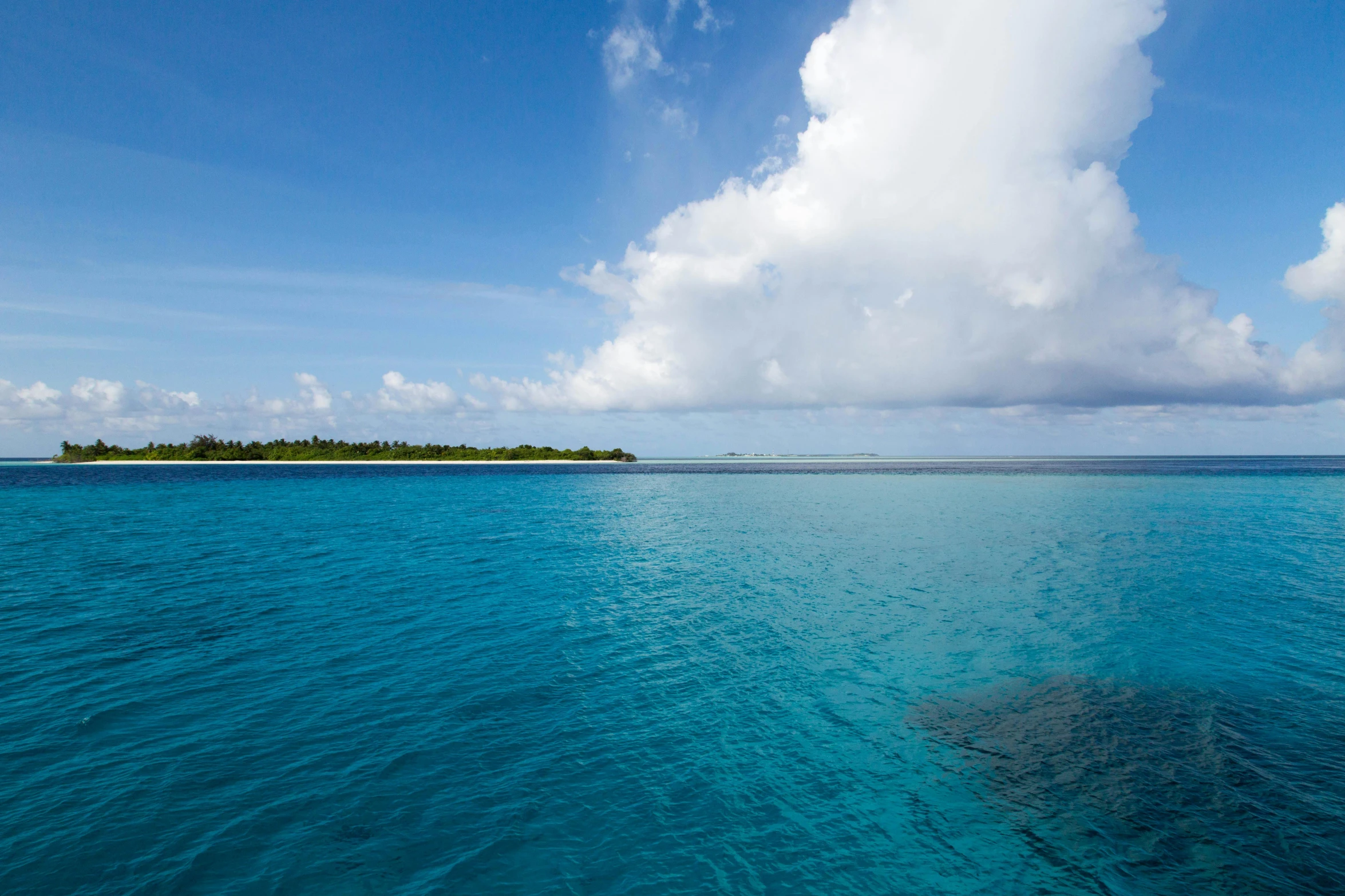 water with small isle and clouds in the distance