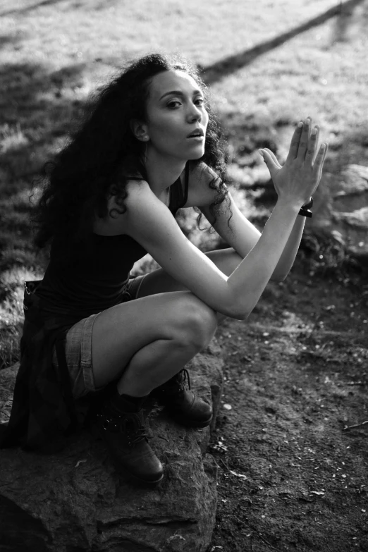 black and white image of a woman sitting on a rock