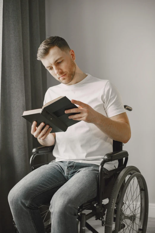 a man is reading a book while sitting in a wheelchair