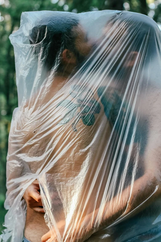 man wrapped in plastic standing in the woods
