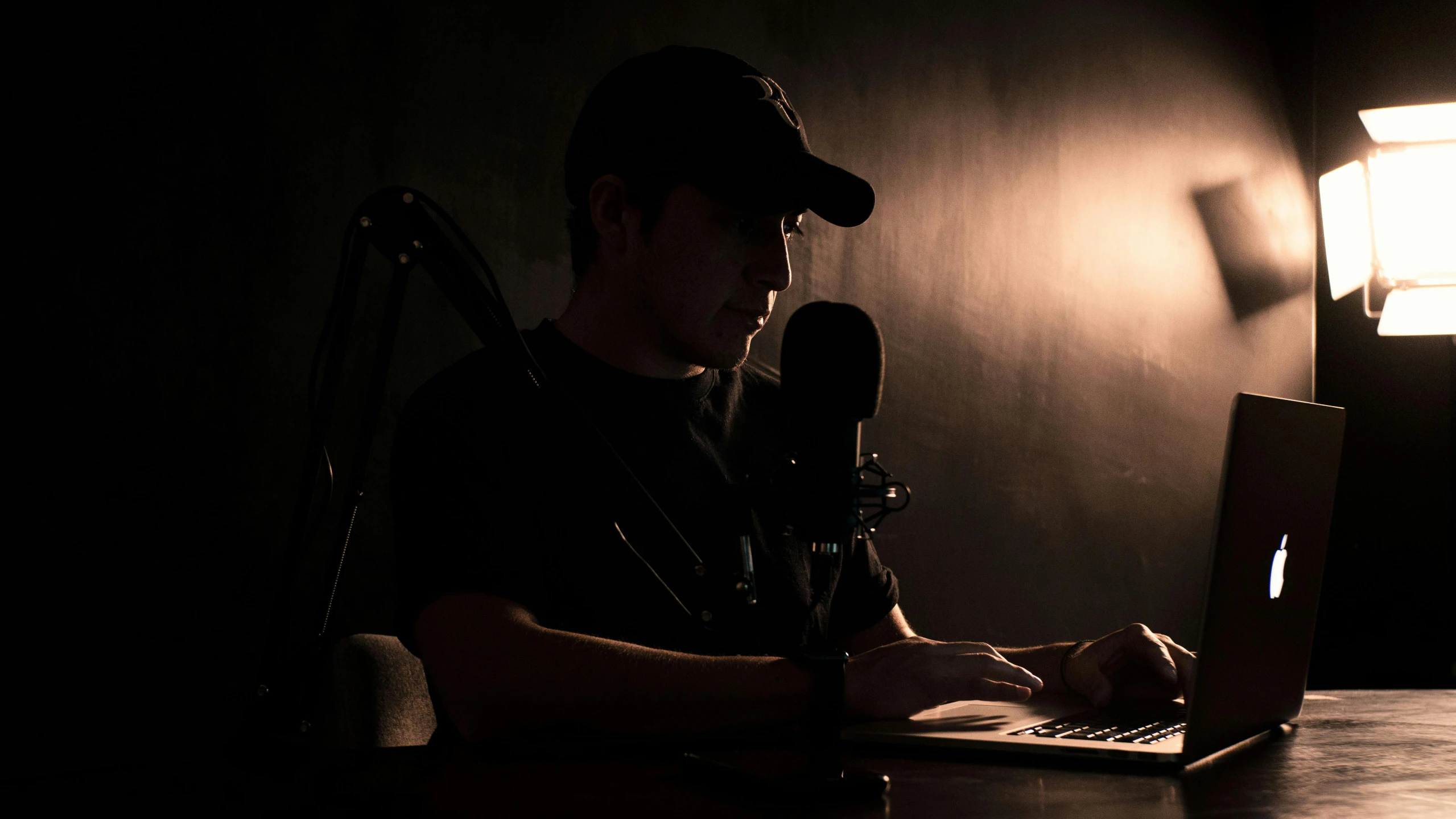 a person sitting at a desk with a laptop computer and microphone