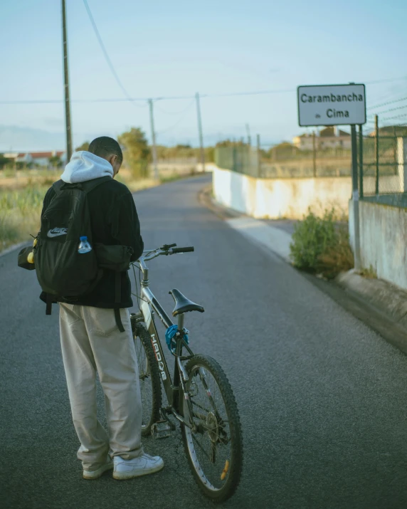 man standing by his bicycle next to the road