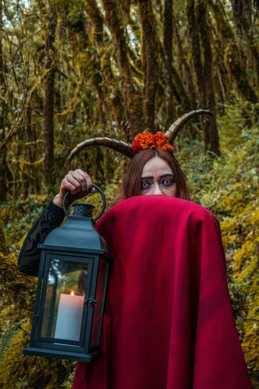 the red dressed woman with horns on her head is holding a lantern