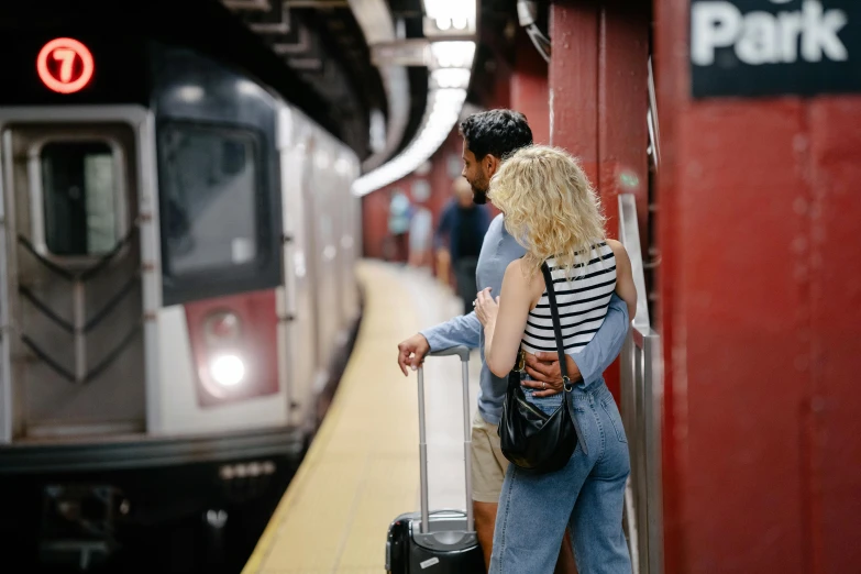 two people are waiting on the train as a commuter prepares to board