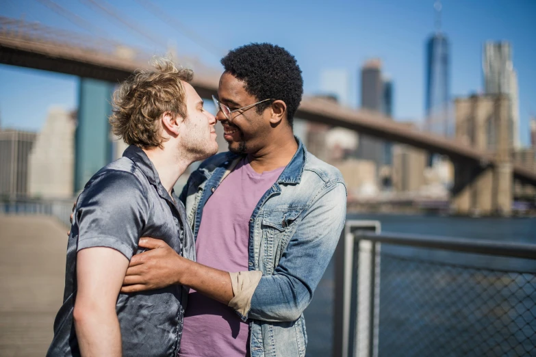 a man giving his friend a kiss on the cheek in a city setting