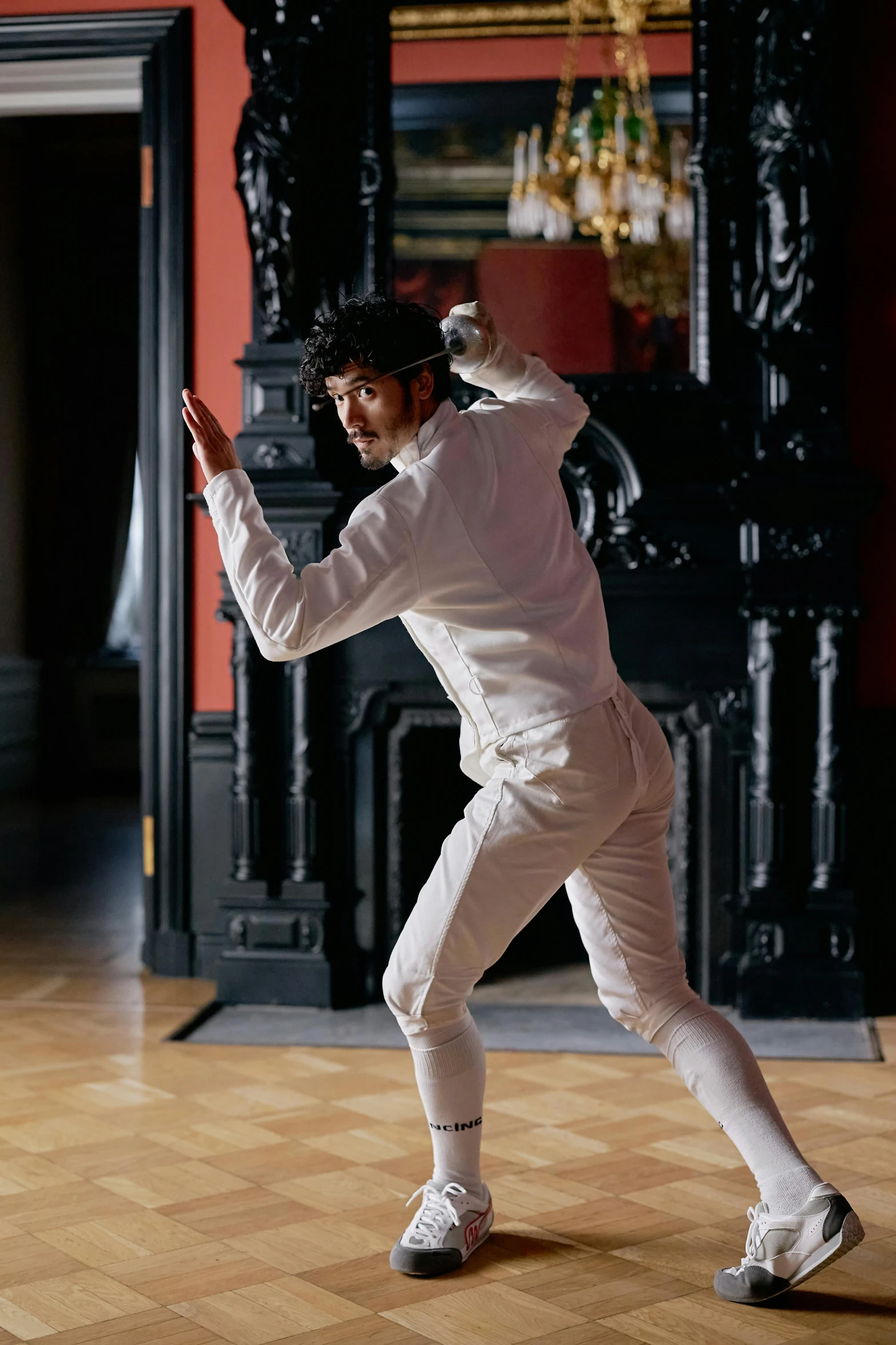 a man wearing white pants standing on a wooden floor