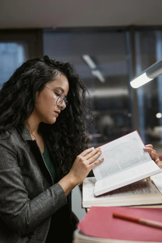 young woman reads a book with her hands at a table