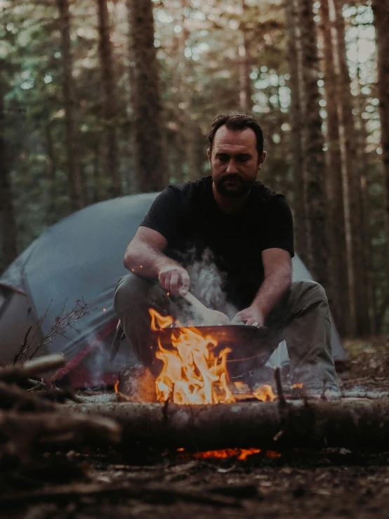 man sitting on his camping chair over a campfire