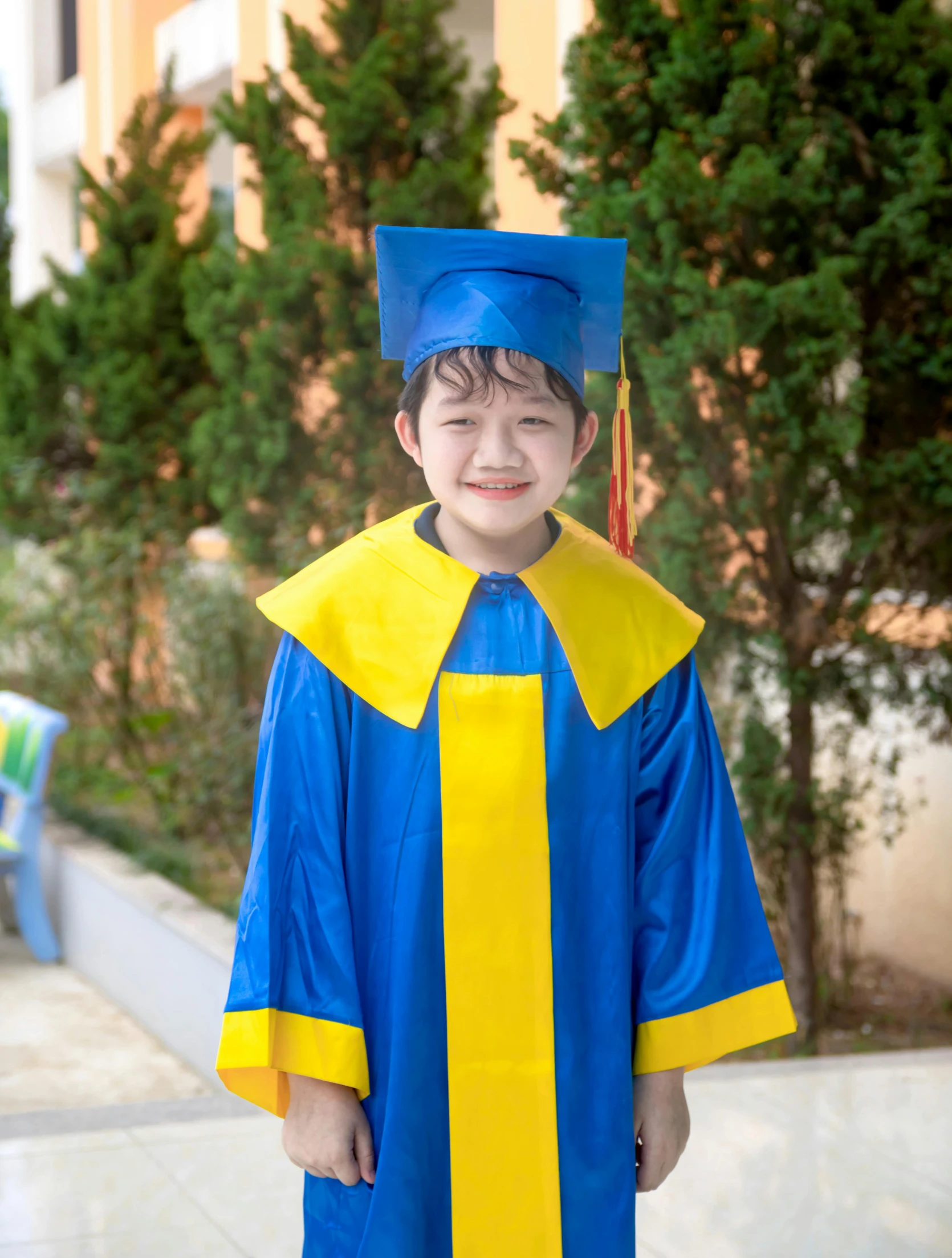 a little boy in a blue and yellow graduation gown