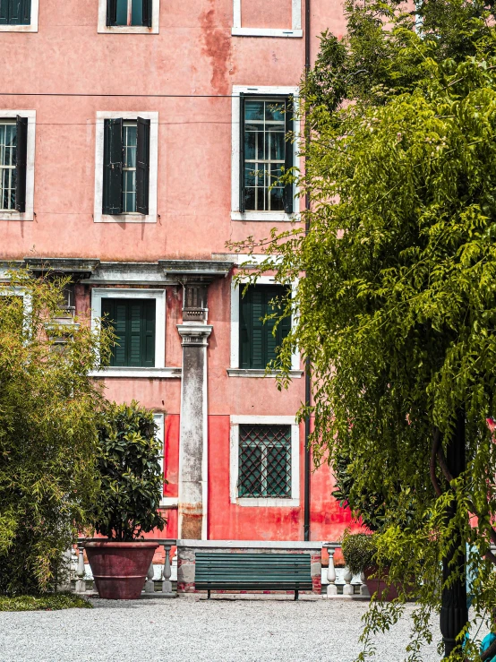 an orange and pink building with a bench in front of it