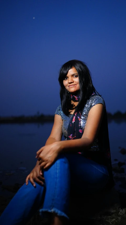 a girl sitting on a rock next to water