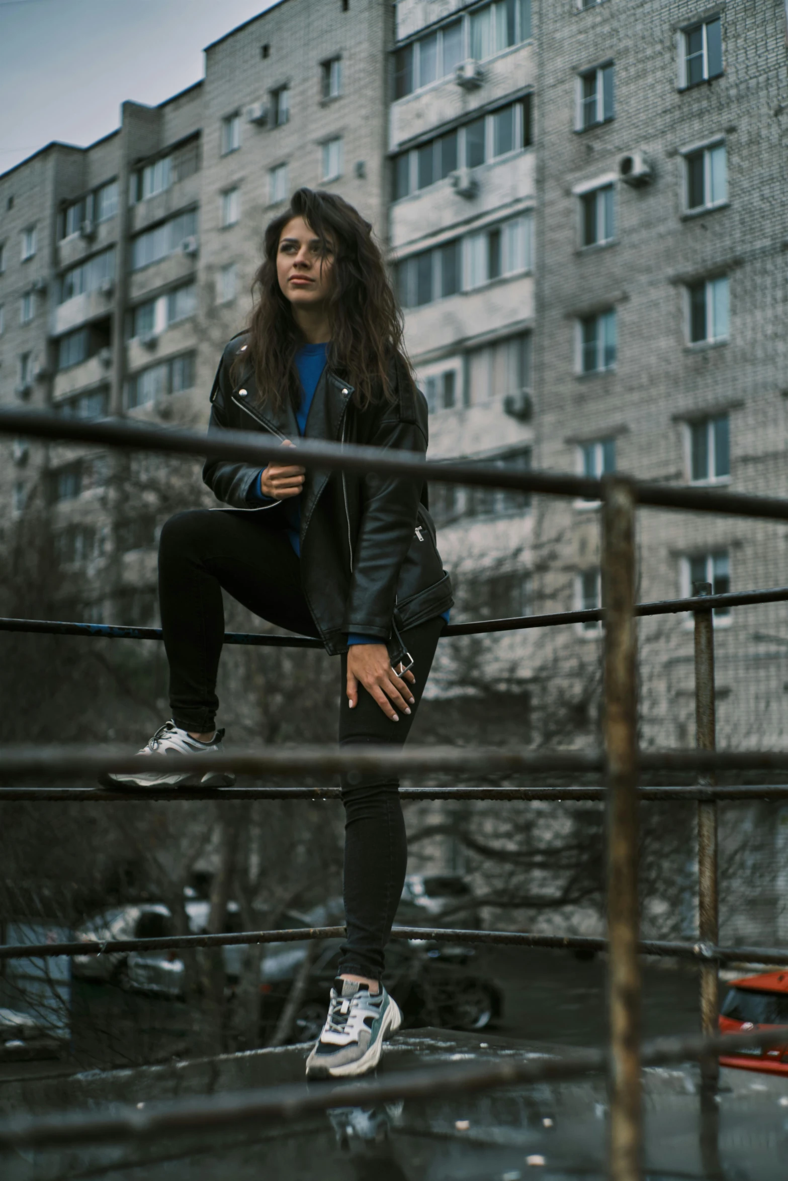 a woman in a black jacket, jeans and tennis shoes