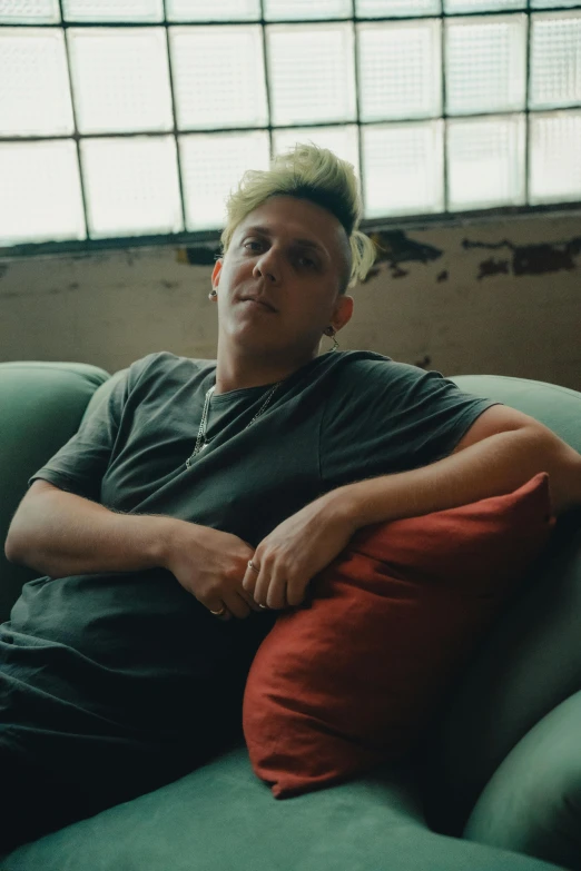 a man sits on the couch with his arm folded