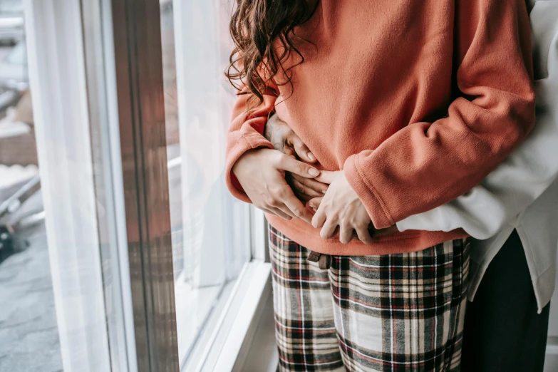 a person standing by a window holding their hands