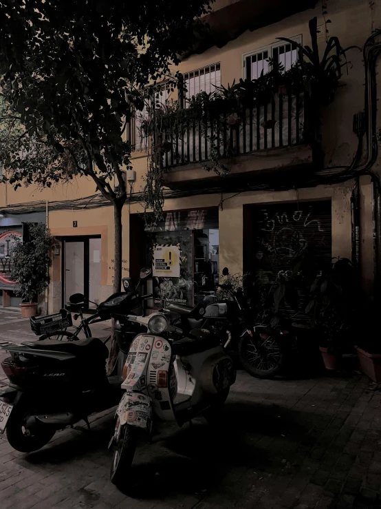 two parked motorcycles sitting outside a building at night