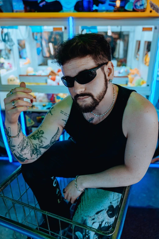 a young man with piercings and sunglasses sitting in a shopping cart