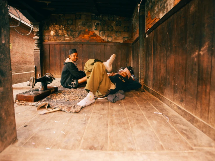 a man and woman sitting on the floor in a corner