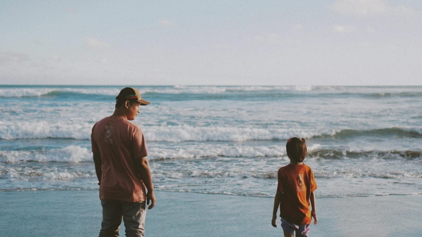 a man and a  are standing on the beach