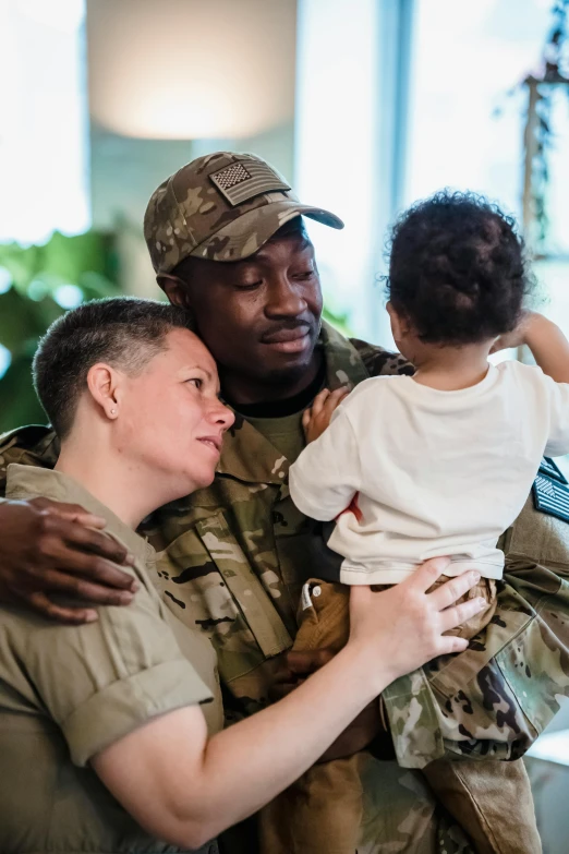 a soldier holds a child as he hugs another soldier