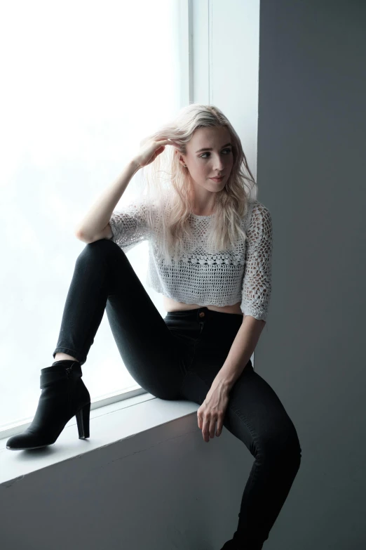 a woman is sitting down on a ledge near a window