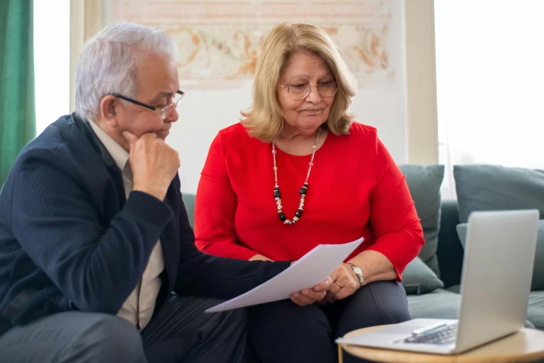 a man and woman sitting next to each other on the couch looking at soing