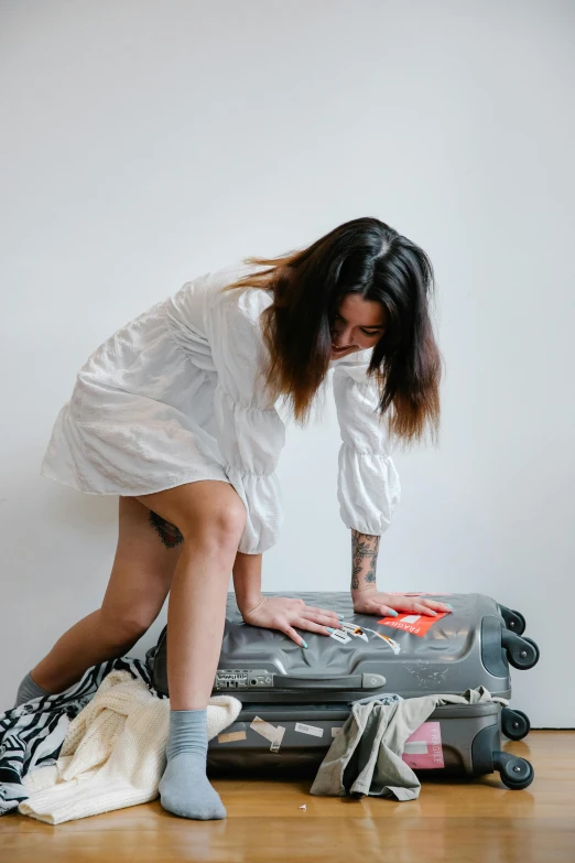 a woman leaning over a luggage bag on the floor