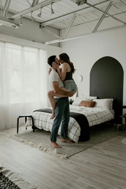 two people standing in front of a bed, one holding the other