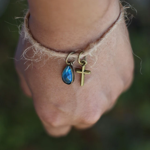 a small religious celet that features a cross and a blue tear