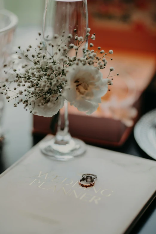 the wedding ring is on a card holder with flowers