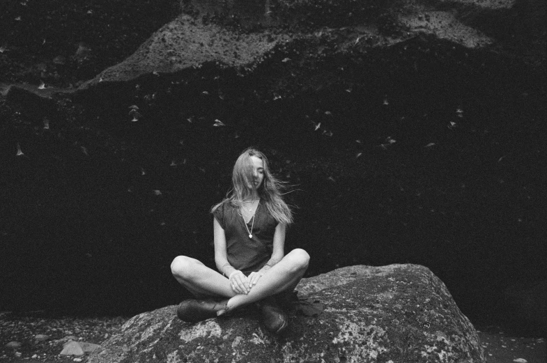 a woman sitting on a rock doing meditation