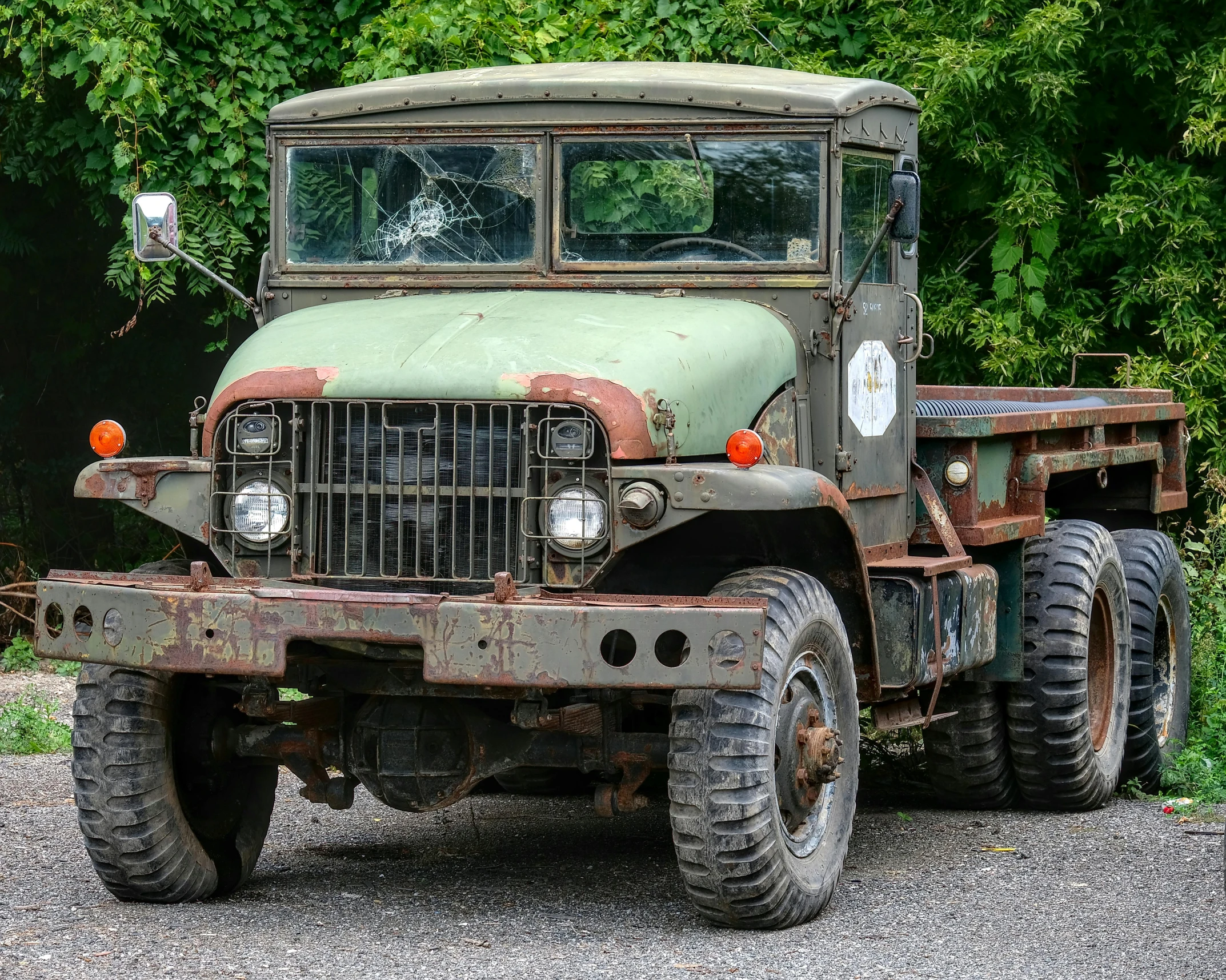 an old army truck is parked near the woods