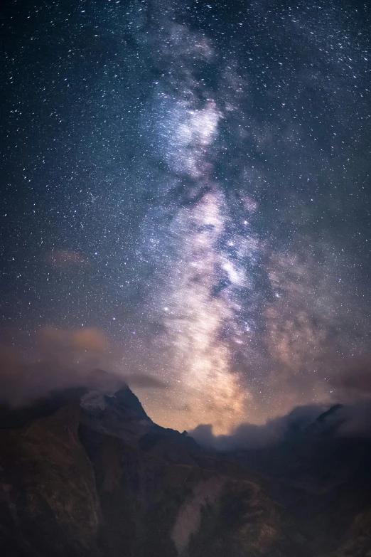 the night sky with some stars above mountains