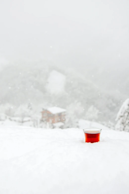 a bucket of  liquid sitting on top of a snowy hillside