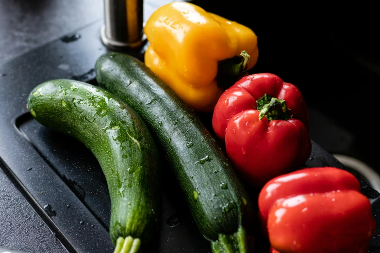 various vegetables such as cucumbers and peppers lay on top of the table