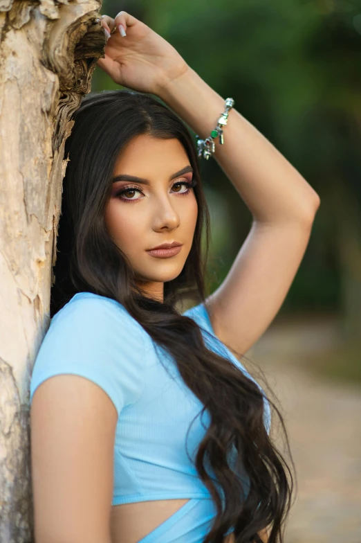 a woman leaning against a tree on a brick walkway