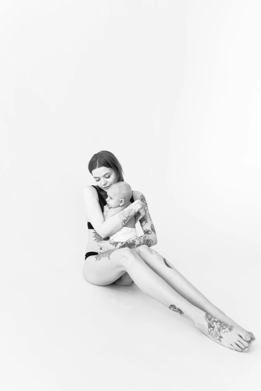 woman sitting in front of white background hugging her little baby