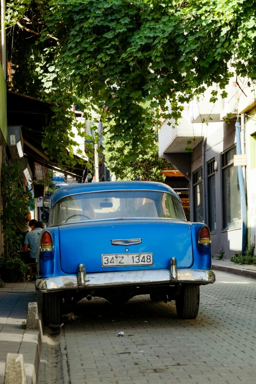 an old blue car parked on the side of the street