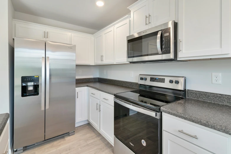 an empty kitchen with stainless steel appliances and white cabinets