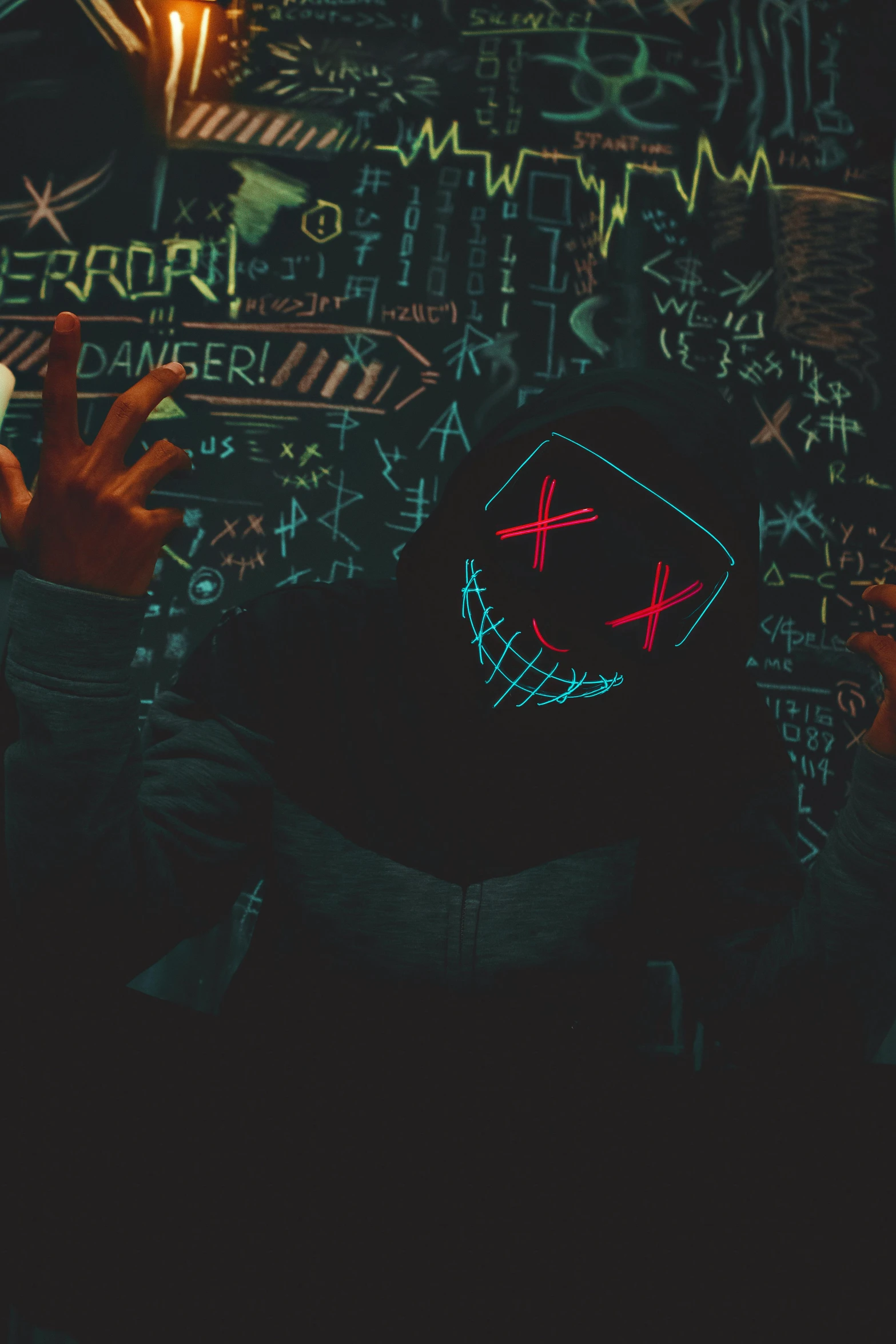 a person with a neon mask on, standing in front of a wall