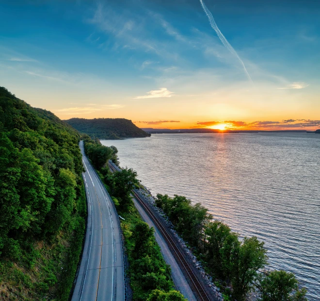 a train on a track by the ocean at sunset