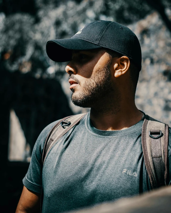 a man standing in the sun wearing a black hat